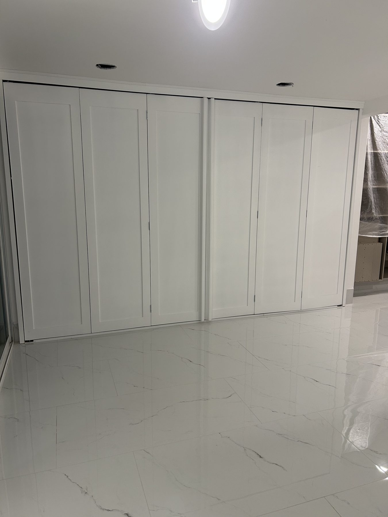 Clóset con puertas plegables blancas estilo shaker sobre piso de mármol