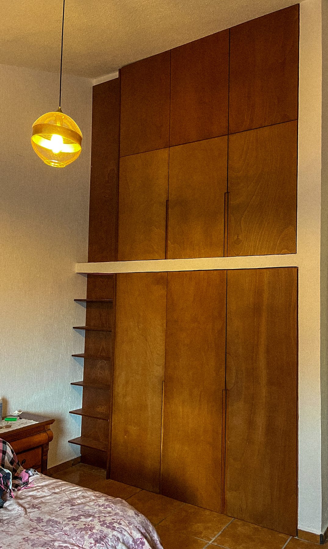 Clóset de madera a doble altura con repisas laterales abiertas