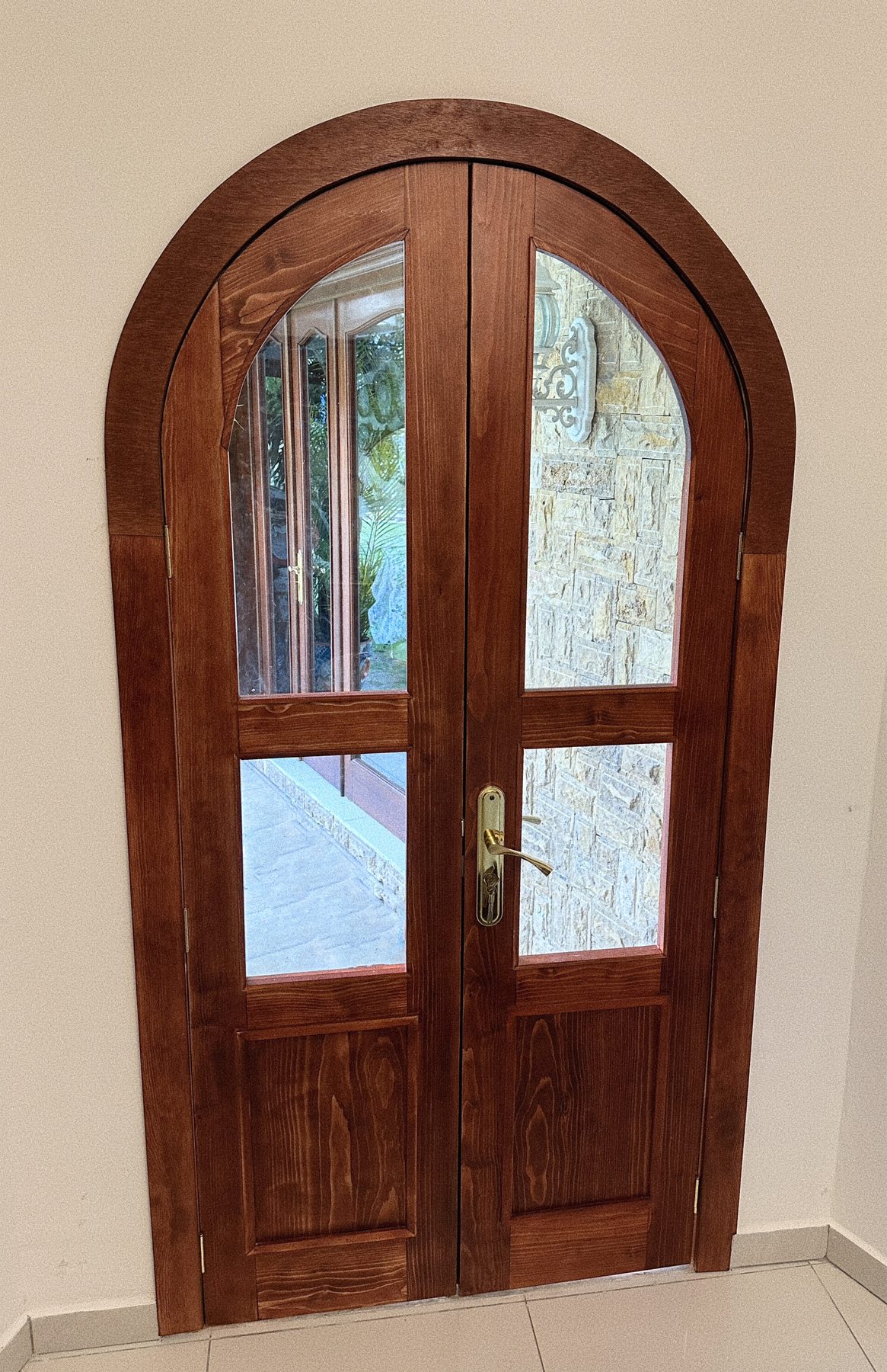 Puerta doble de madera en arco con vidrios y manija dorada